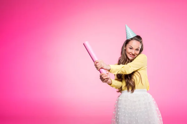 Mulher atraente com chapéu de festa segurando papel como morcego de beisebol isolado em rosa — Fotografia de Stock