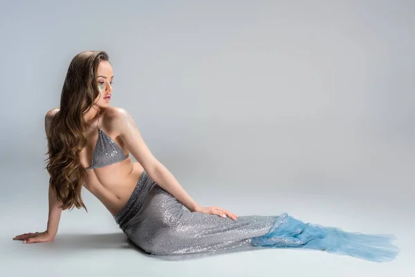 Beautiful woman with mermaid tail lying on floor and looking away — Stock Photo