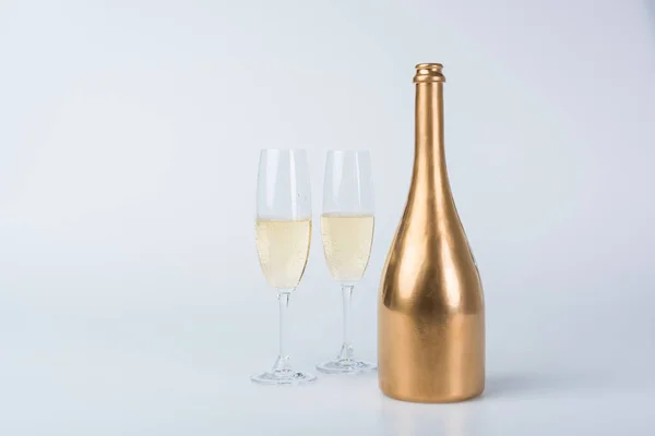 Bottiglia d'oro di champagne e bicchieri su bianco — Foto stock