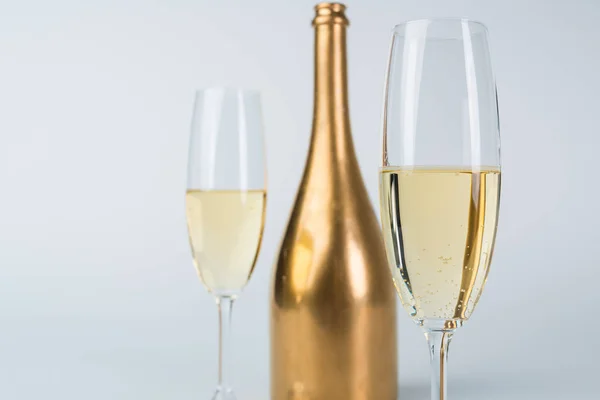 Bouteille de champagne dorée et verres isolés sur blanc — Photo de stock