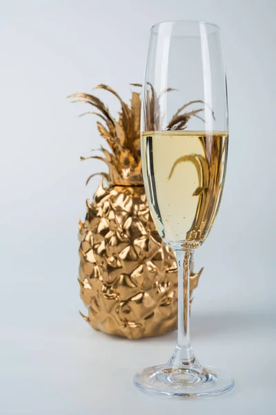 Glass of champagne and golden pineapple on white — Stock Photo
