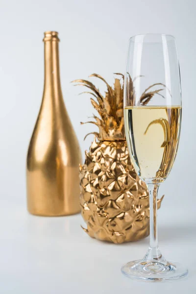 Bouteille dorée de champagne, ananas et verres sur blanc — Photo de stock