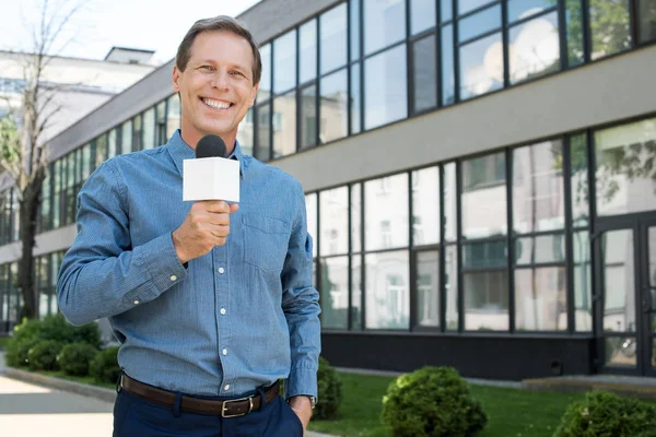 Smiling male mature newscaster with microphone — Stock Photo