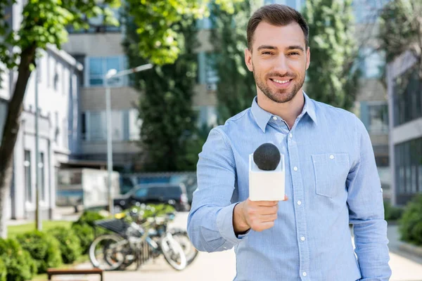 Sonriente reportero de noticias masculino tomando entrevista con micrófono - foto de stock