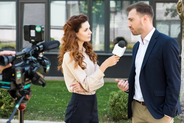 Schöne ernsthafte Reporterin bei einem Interview mit einem Geschäftsmann — Stockfoto