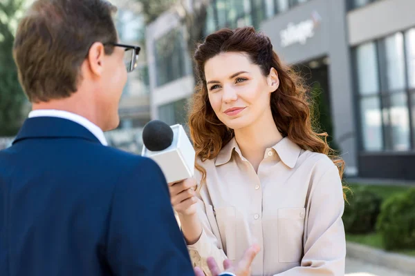 Hermoso periodista con micrófono entrevistando empresario profesional - foto de stock
