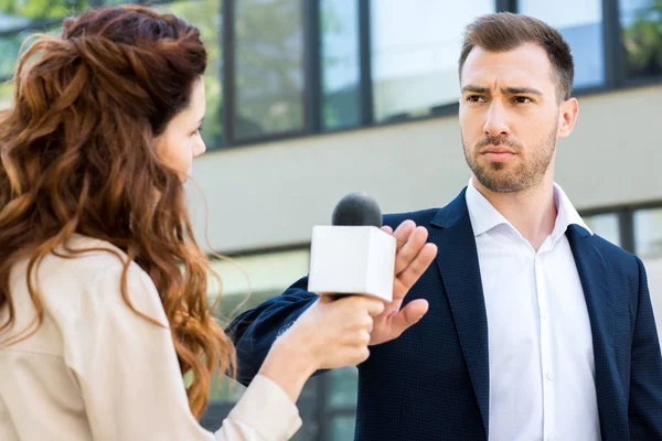 Anchorwoman holding microphone while serious businessman refusing interview — Stock Photo