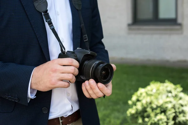 Vista parcial de fotoperiodista en traje con cámara fotográfica digital - foto de stock