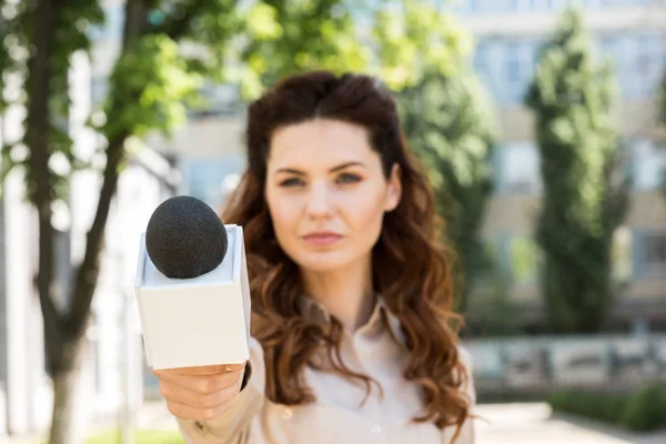Серйозна жінка-журналістка бере інтерв'ю з мікрофоном — стокове фото
