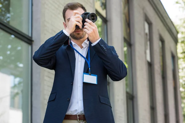 Fotoperiodista en ropa formal con pase de prensa tomando fotos - foto de stock