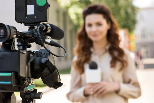 Enfoque selectivo del periodista con micrófono de pie delante de la cámara de vídeo digital - foto de stock
