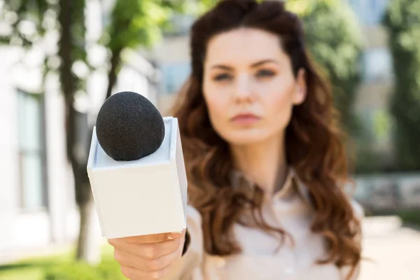 Enfoque selectivo de la presentadora seria teniendo entrevista con el micrófono - foto de stock