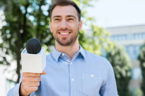 Smiling anchorman taking interview with microphone — Stock Photo