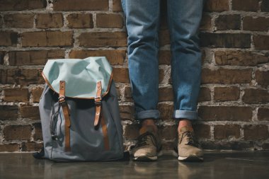 Man with backpack standing near wall clipart