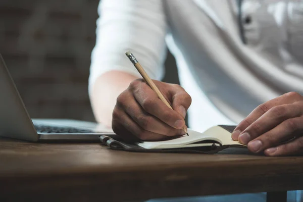 Homem escrevendo em caderno seus planos — Fotografia de Stock