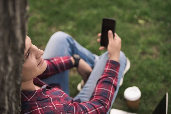 Man using smartphone at park — Stock Photo, Image