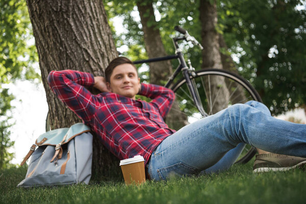 Мужчина расслабляется с чашкой кофе в парке
