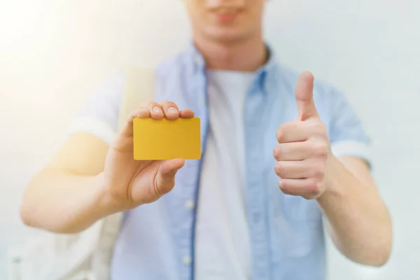 genç adam altın kartı tutan ve başparmak gösterilen kırpılmış atış