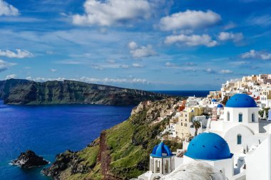 blue-domed churches near white houses and sea in Santorini  clipart