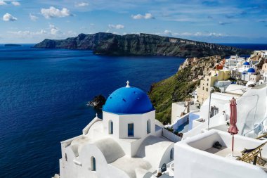 Santorini 'de deniz ve beyaz evlerin yanındaki mavi kubbeli kilise. 