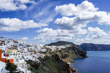 white houses near tranquil sea against blue sky with clouds in greece  clipart