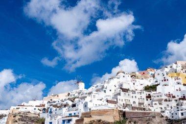 low angle view of white houses near windmill in greece  clipart