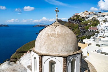 Beyaz evlerin yakınındaki kilisede güneş ışığı ve Santorini adasında sakin bir Ege denizi. 