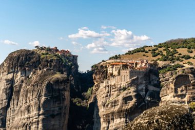 orthodox monasteries on rock formations near mountains in meteora  clipart