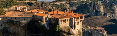 panoramic shot of monastery of holy trinity on rock formations in meteora 