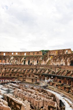ROME, ITALY - APRIL 10, 2020: ruins of historical colosseum against cloudy sky  clipart
