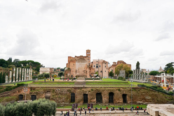 ROME, ITALY - APRIL 10, 2020: people walking near Temple of Venus and Roma against cloudy sky 