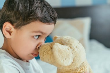 Yüzünün yanında yumuşak oyuncaklar tutan tatlı çocuk. 