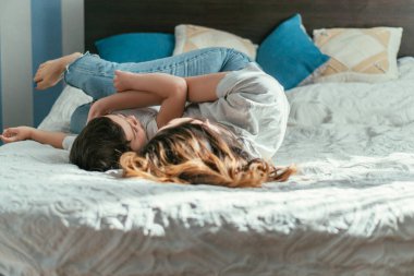 Anne ve bebeğinin yatakta yatışının seçici odağı.