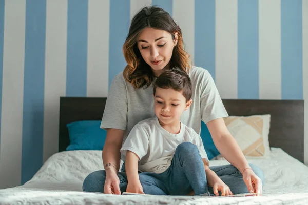 Çekici Anne Kucağında Küçük Oğluyla Yatakta Oturuyor — Stok fotoğraf