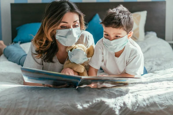 Matka Maluch Syn Maskach Medycznych Czytanie Książki Pobliżu Miękkiej Zabawki — Zdjęcie stockowe