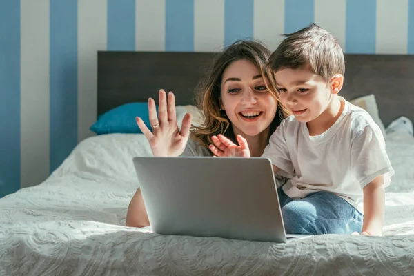 幸せな母親と幼児男の子手を振りながらビデオ通話でベッドルーム — ストック写真