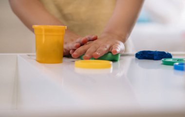 Renkli plastikle heykel yapan küçük bir çocuk manzarası.