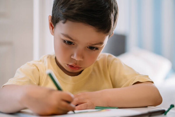 selective focus of cute, focused boy drawing with felt-tip pen