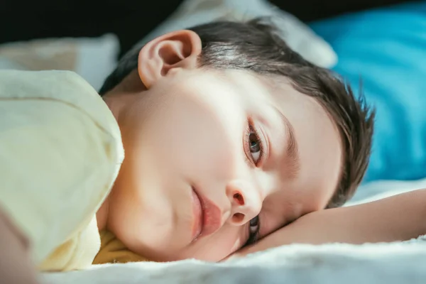 Stock image adorable boy looking at camera while lying on bed