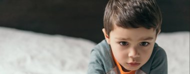Yatakta yatan düşünceli çocuğun yatay görüntüsü.