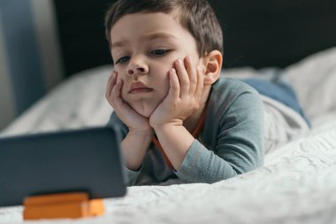 Akıllı telefondaki düşünceli, dikkatli çocuk Webinar 'ın seçici odağı.