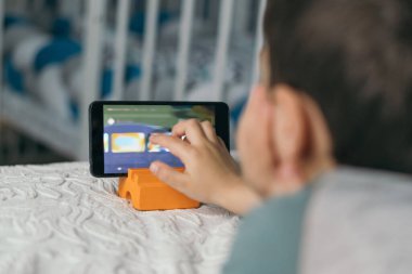 İnternet dersini izlerken akıllı telefonun ekranına dokunan küçük çocuğun seçici odak noktası