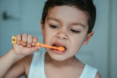 Banyoda dişlerini fırçalayan tatlı, konsantre bir çocuk.