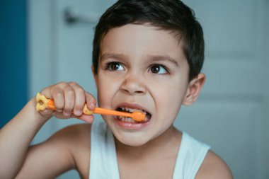 Banyoda dişlerini fırçalarken gözlerini kaçıran sevimli küçük çocuk.