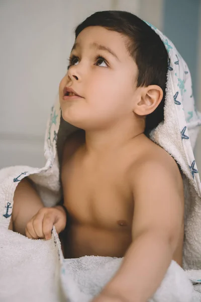Wybiórcze Skupienie Uroczego Chłopca Owiniętego Zakapturzony Ręcznik Patrzącego Górę Siedzącego — Zdjęcie stockowe