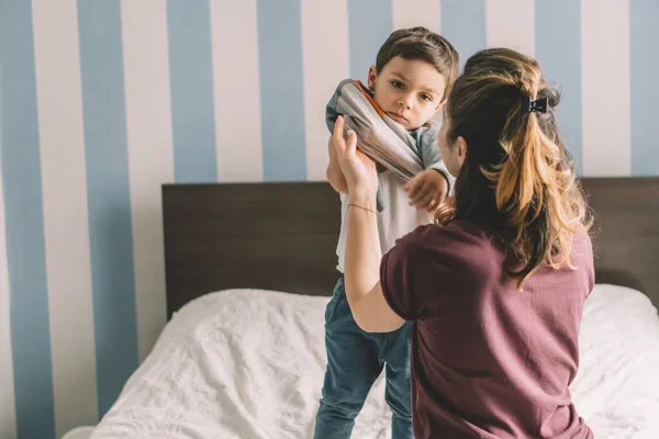 Back View Mother Dressing Adorable Son Bedroom — Stock Photo, Image