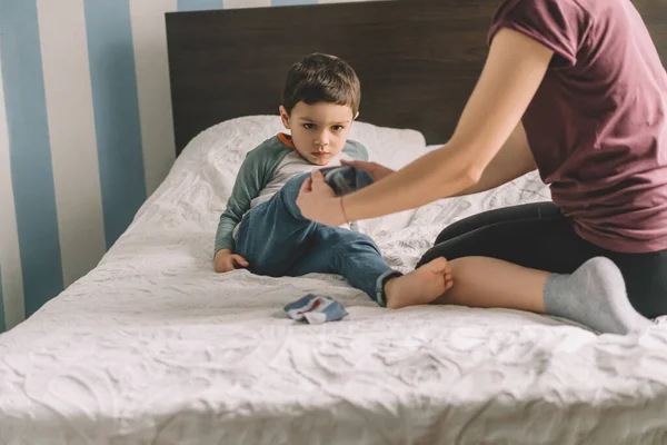 Partiell Bild Kvinna Dressing Bedårande Son När Sitter Sängen — Stockfoto