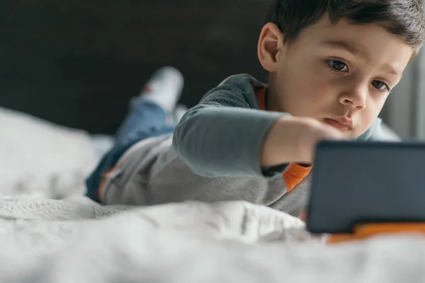 Foco Seletivo Menino Bonito Tocando Smartphone Enquanto Deitado Cama — Fotografia de Stock