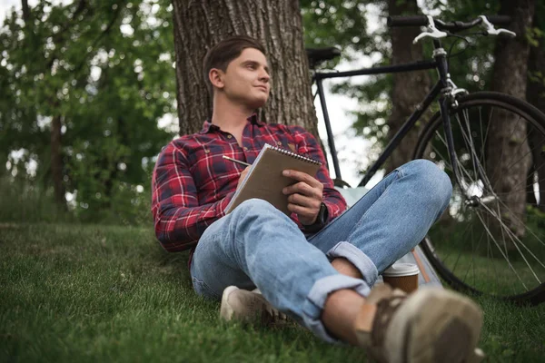 Junger Mann macht sich Notizen in Notizbuch — Stockfoto