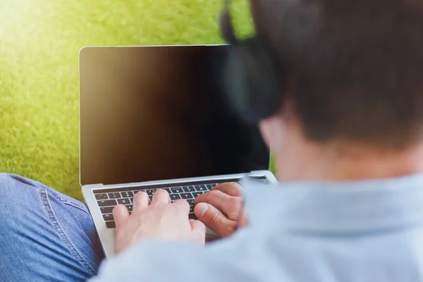 Close-up tiro de homem em fones de ouvido usando laptop — Fotografia de Stock